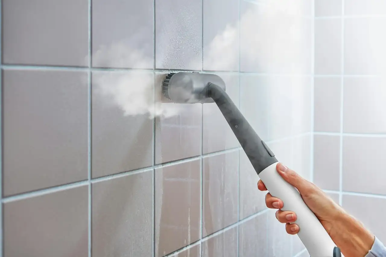 Steam brush lifting grime out of tile grout during a deep clean